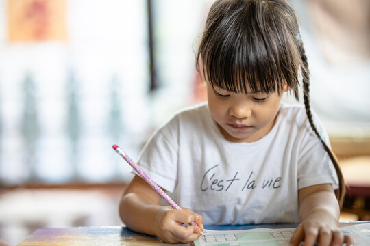 A cute 3-year-old Asian girl is practicing writing. It is an image that focuses on the subject behind blur. concept of hand muscle training