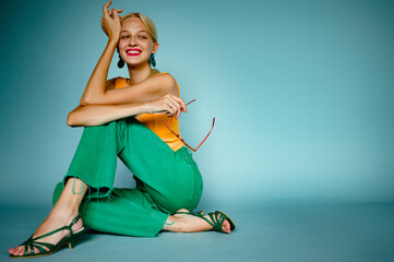 Happy smiling fashionable woman wearing trendy green color wide leg jeans, strappy sandals, posing,...