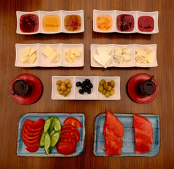 mediterranean breakfast table with tomatoes, cucumbers, cheese, jams, olives, black tea, watermelon.