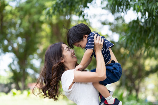 Happy Asian family playing together outdoor. Cheerful mother and little son having fun and relaxing on holiday in the the park. Mom spending time with little son on vacation. Happy family and holiday