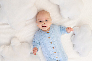 baby on the bed among the cloud pillows. Textiles and bedding for children.