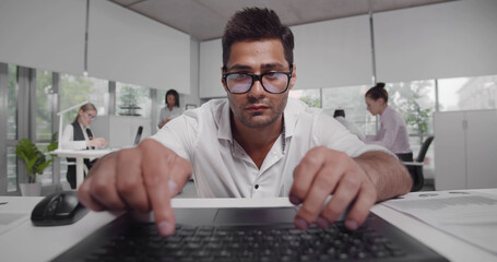 Fototapeta na wymiar Handsome confident businessman sit down at workplace work on laptop looking at screen