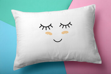 Soft pillow with cute face on color background, top view