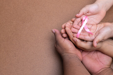 hands holding pink ribbon, breast cancer, chocolate background