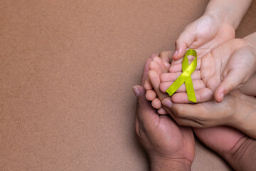 hands holding green cane ribbon, lymphoma cancer, chocolate background