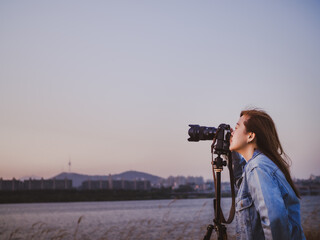 hobby and lifestyle in autumn to winter season travel activity from hipster woman photographer during setting and take photo by her camera to beautiful bridge and river during sunset background