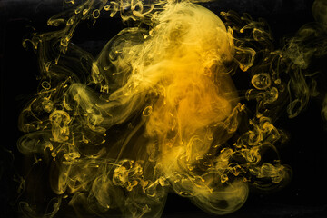 Abstract liquid art, yellow smoke bomb on black background, amber color acrylic paints under water