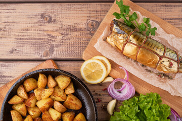 Fototapeta na wymiar Composition smoked mackerel fish with garnish potatoes lemon greens onions served on wooden board plate top view