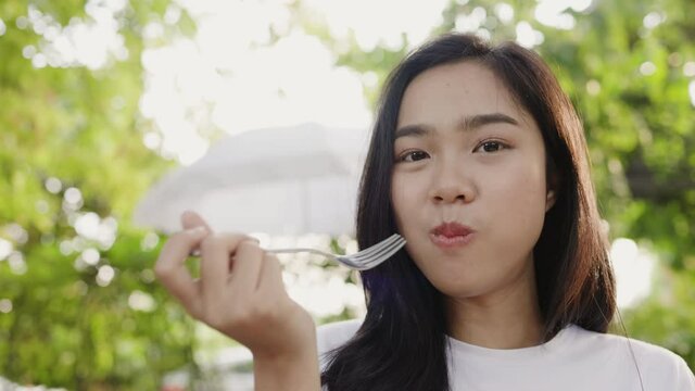 Asian teenage woman enjoy eating delicious salmon fillet in garden at home. satisfied with taste of food ordered from delivery. Weekend activity happy restaurant lifestyle concept. 