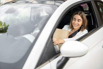 Woman drives a car with parcels in her hands
