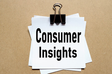 Consumer Insights. the paper is clamped with a clerical clip. paper on wood background.