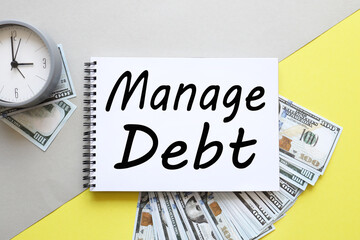 MANAGE DEBT. gray and yellow background. the inscription on the notebook near the money