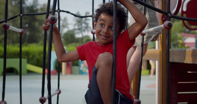 Portrait of african child climbing on rope ladder on playground