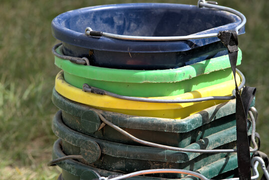 Close up of different colored feed buckets used in a horse facility.