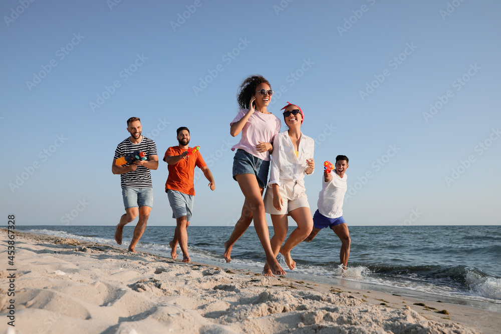 Wall mural group of friends with water guns having fun on beach