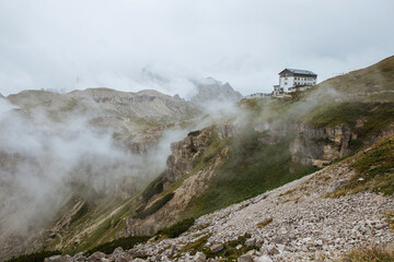 Moody picture of Dolomite peaks. Autumn in Dolomites. Huge peaks in clouds in Italy. Refugio Auronzo. 