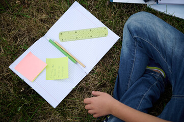 Flat lay of open notebook with colorful note papers with arithmetic problems, pencil, ruler and pen...