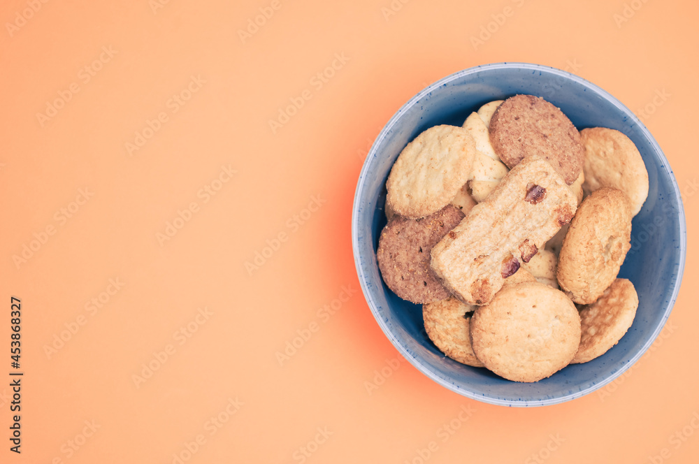 Poster Vertical shot of organic biscuits in a blue bowl on orange background