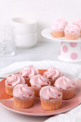 A plate of pink mini cupcakes in a white kitchen setting