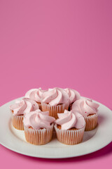 A plate of strawberry pink mini cupcakes on a pink background