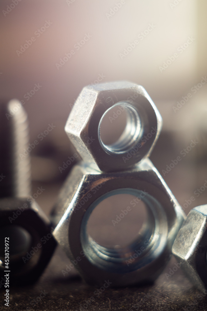 Wall mural Vertical shot of two one on another big and small metal nuts against a gray background