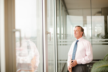 Fototapeta premium Businessman standing at office window