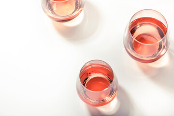 Rose wine glasses on white background. Wine tasting, top view, negative space