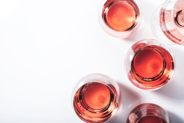 Rose wine glasses on white background. Wine tasting, top view, negative space