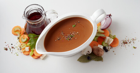 Sauce bowl placed on table with scattered veggies and vinegar carafe