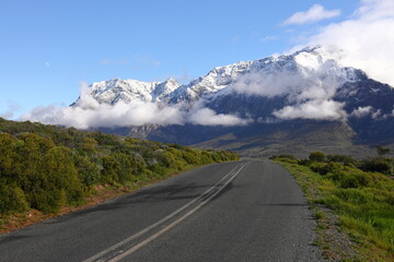 A view over green hills towards snow covered peaks