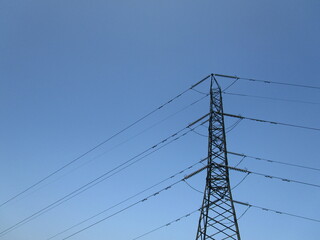 Torre de alta tensi&oacute;n en contrapicado con fondo de cielo azul
