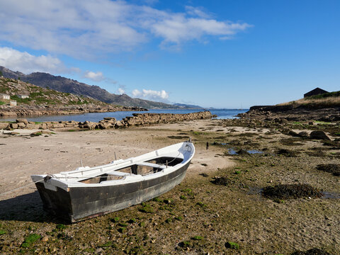 Low tide with a traditional fishing rowboat in the Galician coast, Northern Spain.
