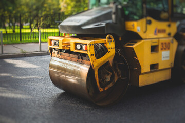 Process of asphalting, blacktopping and paving, asphalt paver machine and steam roller compactor during construction and repairing works, workers on the construction site, rental vehicle working
