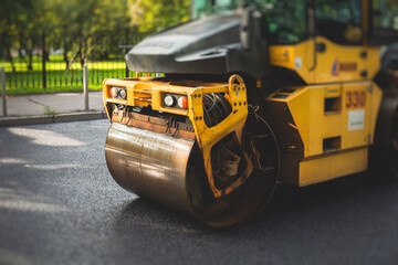 Obraz premium Process of asphalting, blacktopping and paving, asphalt paver machine and steam roller compactor during construction and repairing works, workers on the construction site, rental vehicle working