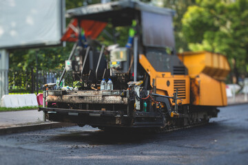 Process of asphalting, blacktopping and paving, asphalt paver machine and steam roller compactor during construction and repairing works, workers on the construction site, rental vehicle working