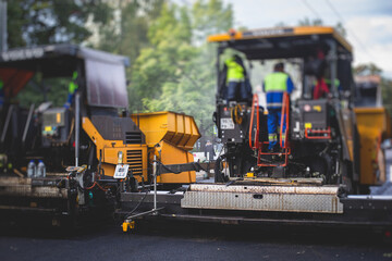 Process of asphalting, blacktopping and paving, asphalt paver machine and steam roller compactor during construction and repairing works, workers on the construction site, rental vehicle working