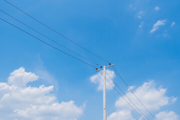 Electric pole and cable line with white clouds and blue bright sky background