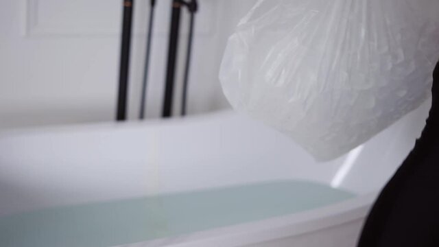 Man filling bath with ice cubes for recovery and health purposes