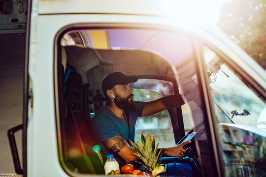 Young bearded man is driving delivery van. He is working in everyday or daily home delivery service.