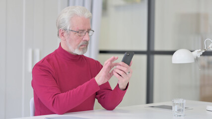 Old Man Browsing Internet on Smartphone at Work 