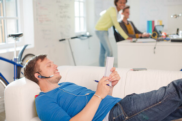 Obraz premium Man in headset taking notes on sofa