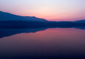 Fototapeta premium Hazy purple sunset over Lake McDonald in Glacier National Park, MT