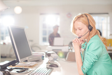 Businesswoman talking on headset at desk