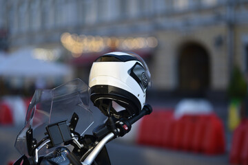 Obraz premium helmet hanging on motorcycle handlebar against traffic barriers in selective focus