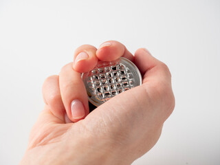 A man's hand holds a used aluminum coffee capsule on a white background. Modern ways of storing coffee