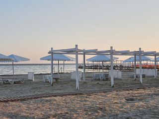 Fototapeta na wymiar Sunbeds and umbrellas on the beach are waiting for vacationers. Summer vacation at sea.