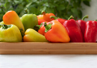 Sweet red pepper in a wooden tray on a white table