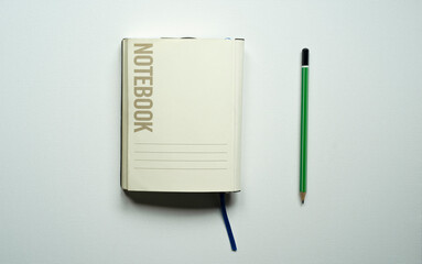 notebook with space for text, desk, blue bookmark, green pencil, on a white background, photo from above