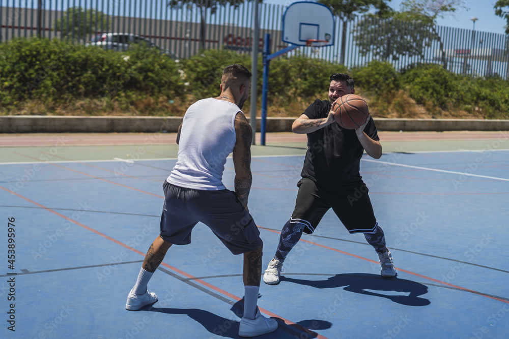 Sticker two young males playing basketball on the outdoor court