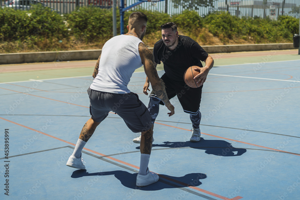 Canvas Prints Two young males playing basketball on the outdoor court